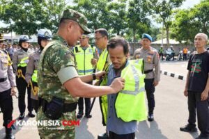 Dandim 0506/Tgr Kolonel Inf M. Alharidz Unus, memakaikan rompi reflektif kepada seorang warga, disaksikan personel kepolisian dan petugas lalu lintas saat Operasi Patuh Jaya 2026