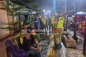 Personel Koramil 02/Pondok Gede dan Mitra Jaya berbincang dengan warga di trotoar saat patroli gabungan malam hari di Bekasi