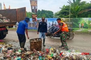 Petugas Koramil Panongan dan DLHK mengangkat sampah liar di Jalan Raya Serdang Kulon ke truk pengangkut.