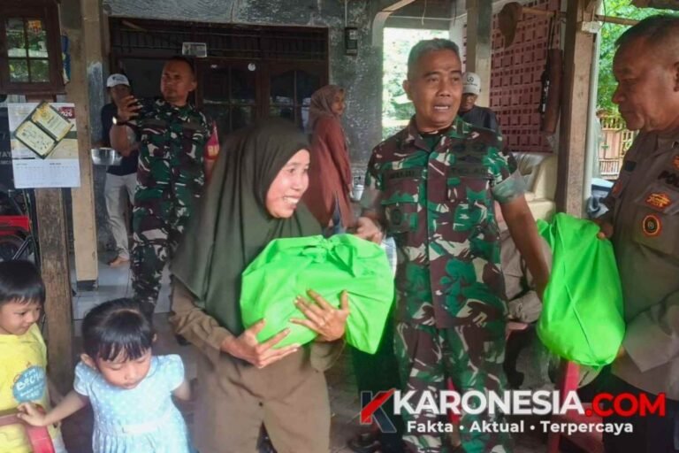 Danramil Pondok Aren Mayor Inf Jajang Munajat dan personel Polri menyerahkan paket bantuan sembako yang dibungkus kain hijau kepada seorang warga perempuan di Parigi Lama.