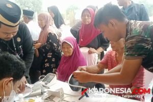 Prajurit Satgas TMMD 130 Kodim 0510 Tigaraksa membantu memeriksa tensi darah lansia di Lapangan Bendung Jayanti.