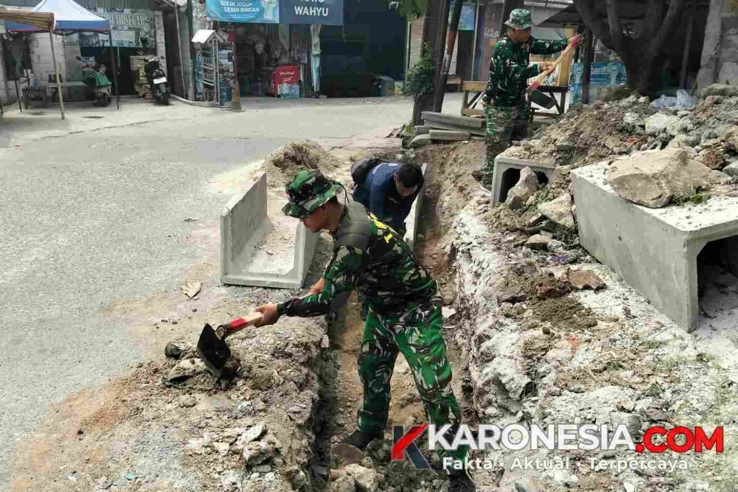 Anggota Satgas TMMD 130 Kodim 0510 Tigaraksa menggali tanah menggunakan cangkul untuk membuat parit drainase di Desa Sumur Bandung.