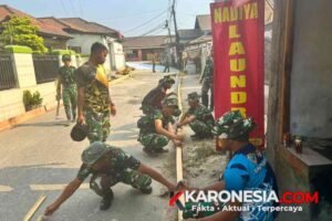 Prajurit Satgas TMMD Kodim 0510 Tigaraksa membahu papan bekisting kayu untuk persiapan pengecoran jalan desa.