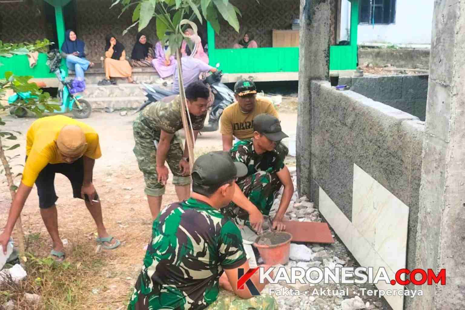 Prajurit TNI dan warga bergotong royong memasang keramik tandon air bersih di Kampung Kramat