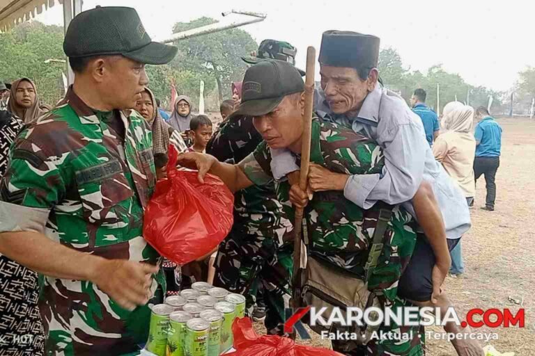 Anggota TNI Kodim Tigaraksa membopong lansia Pak Said saat menerima bantuan sembako di lokasi TMMD.