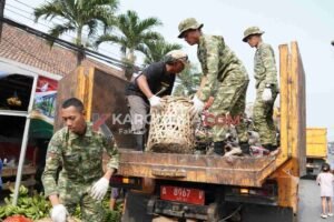 Personel TNI Kodim 0510 Tigaraksa bersama warga menaikkan keranjang sampah ke atas truk saat karya bakti di Pasar Gembong Balaraja Tangerang.
